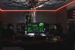 Team of hackers with Guy Fawkes masks coding in a dark room with computers.